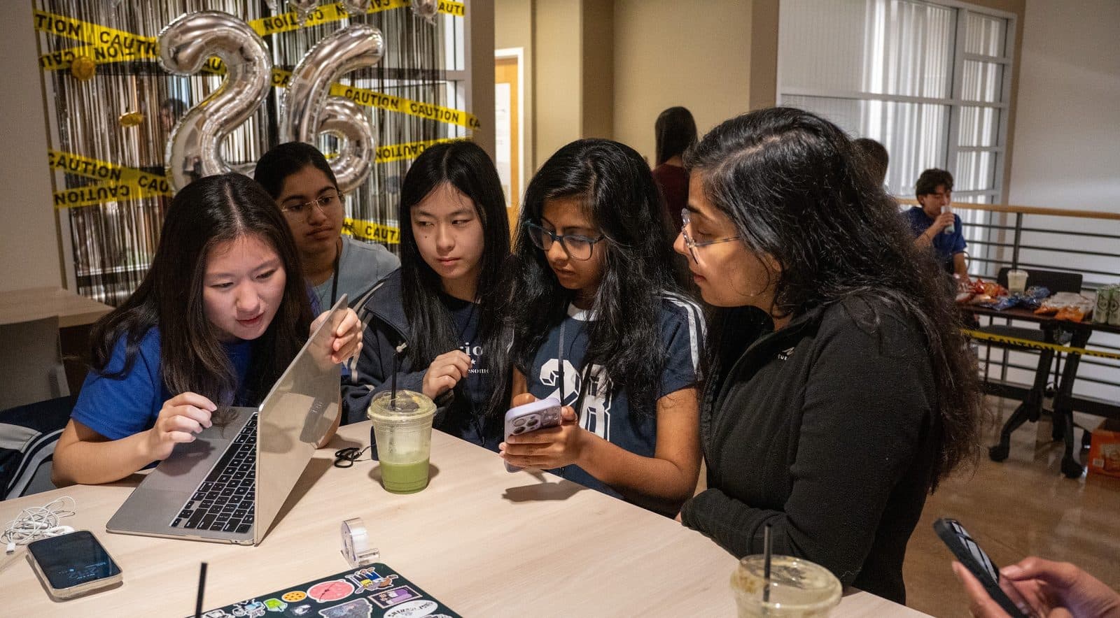 Members huddled around a laptop at a decorated social